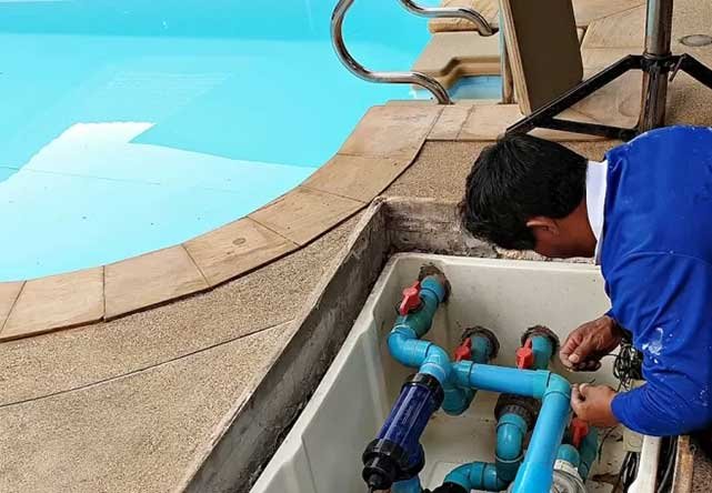 فني يفحص مضخات وصمامات المسبح